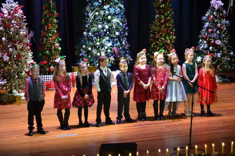 Kids singing on stage with Christmas trees