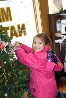 Girl putting ornament on Christmas tree