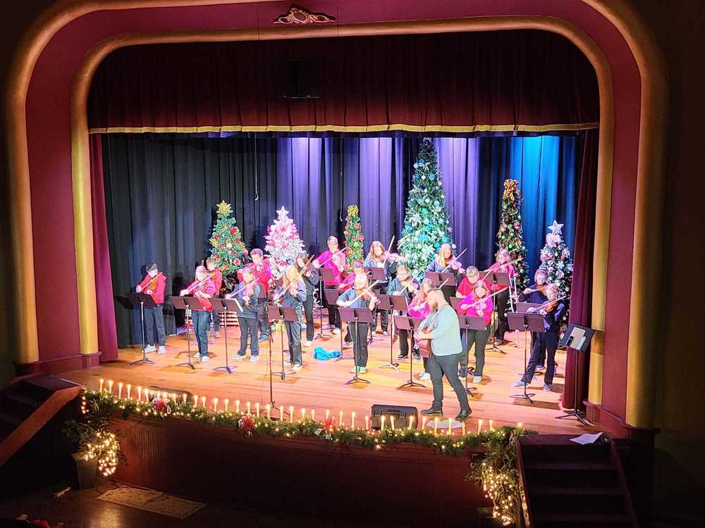 Students playing violin on a stage